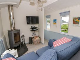A living room with a stove and television at Clifftop Carriage in Aberporth, Ceredigion