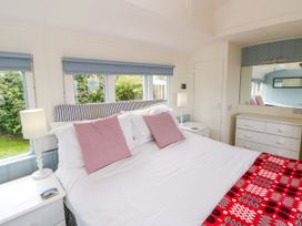 A bedroom with a bed and furniture at Clifftop Carriage in Aberporth, Ceredigion