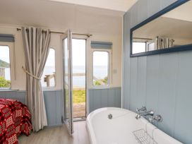 A bathroom with a bathtub and window at Clifftop Carriage in Aberporth, Ceredigion