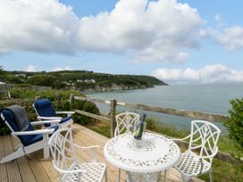 A patio area with chairs and table overlooking the ocean at Clifftop Carriage in Aberporth, Ceredigion