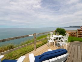 An outdoor area with a table and chairs overlooking the ocean at Clifftop Carriage Aberporth, Ceredigion