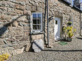 A stone wall with a window and door at End Cottage in Newport, Pembrokeshire