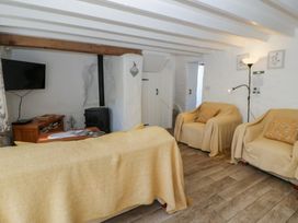 A living room with a television and wood stove at End Cottage in Newport, Pembrokeshire