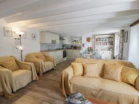 A living room with a sofa and kitchen area at End Cottage in Newport, Pembrokeshire