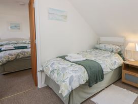 A bedroom with two beds and a bedside table at End Cottage Newport, Pembrokeshire