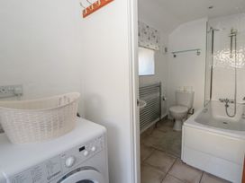 A bathroom with a washing machine and bath at End Cottage in Newport, Pembrokeshire