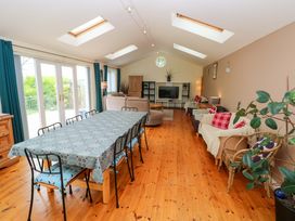 A living room with a dining table and a sofa at Greenbanks in Dinas Cross, Pembrokeshire