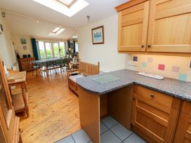 A kitchen with wooden cabinets and a table in Greenbanks, Dinas Cross, Pembrokeshire