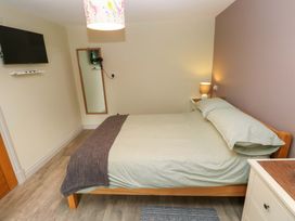 A bedroom with a bed, lamp, mirror, and tv at Greenbanks, Dinas Cross, Pembrokeshire