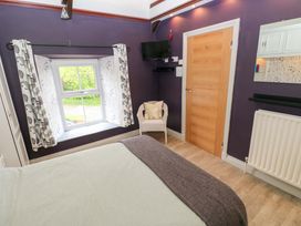A bedroom with a bed, window, and a chair at Greenbanks in Dinas Cross, Pembrokeshire