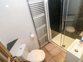 A bathroom with a toilet, shower, towel rail, and sink at Greenbanks in Dinas Cross, Pembrokeshire