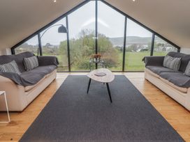 A living room with two sofas and a coffee table in front of a large triangular window with a view of the countryside at The Willows in Newport Pembrokeshire