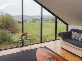 A living room with large triangular windows showing a field and houses at The Willows in Newport Pembrokeshire