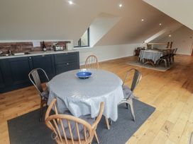 A kitchen and dining area with wooden floors two tables with tablecloths and chairs at The Willows in Newport Pembrokeshire