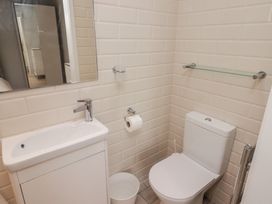 A bathroom with a white sink cabinet mirror toilet roll holder and glass shelf at The Willows in Newport Pembrokeshire
