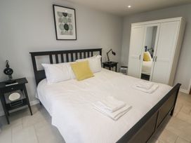 A bedroom with a black bed frame white bedding yellow pillow two bedside tables and a white wardrobe with mirror at The Willows in Newport Pembrokeshire