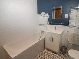 A bathroom with a bathtub a sink with cabinet a mirror and patterned floor tiles at The Willows in Newport Pembrokeshire