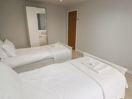 A bedroom with two single beds with white bedding a wardrobe with a mirror and a wooden door at The Willows in Newport Pembrokeshire