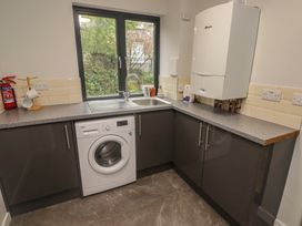A laundry room with a washing machine a sink countertop cabinets and a window at The Willows in Newport Pembrokeshire