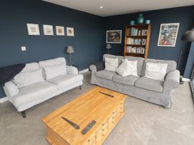 A living room with two gray sofas a wooden coffee table a bookcase and pictures on blue walls at The Willows in Newport Pembrokeshire