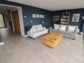 A living room with two sofas a wooden coffee table a bookshelf and blue walls at The Willows in Newport Pembrokeshire
