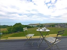 A balcony with two chairs and a table with a teapot and cups overlooking fields and houses at The Willows in Newport Pembrokeshire