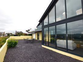 An outdoor patio with a black metal table and chairs next to a modern building with large glass windows at The Willows in Newport Pembrokeshire