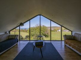 A living room with large windows showing the view at The Willows in Newport, Pembrokeshire