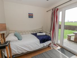 A bedroom with a bed and door leading to outdoor space at Y Felin in Cardigan, Ceredigion