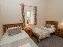 A bedroom with two single beds and a window at Y Felin in Cardigan, Ceredigion
