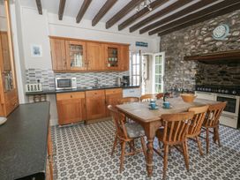 A kitchen with wooden cabinets and a dining table at Dewi Villa in Aberarth, Ceredigion
