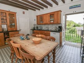 A kitchen with a wooden table and chairs at Dewi Villa in Aberarth, Ceredigion