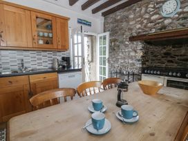 A kitchen with wooden cabinets and a dining table at Dewi Villa in Aberarth, Ceredigion
