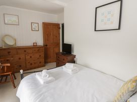 A bedroom with a bed, dresser, and television at Dewi Villa in Aberarth, Ceredigion