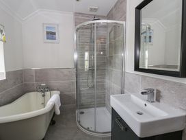A bathroom with a bathtub, shower, and sink at Dewi Villa, Aberarth, Ceredigion