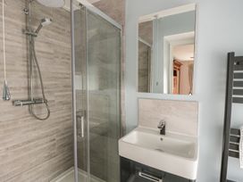 A bathroom with a shower, sink, and mirrors at Dewi Villa in Aberarth, Ceredigion