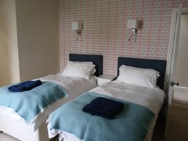 A bedroom with two beds and a bedside table at Lyndale in Newport, Pembrokeshire
