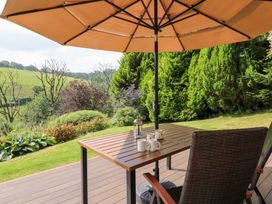 A garden area with a table and chairs under an umbrella at Dan Castell Cottage in Llandeilo, Carmarthenshire
