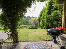 A garden with a barbecue grill and flowers at Dan Castell Cottage in Llandeilo, Carmarthenshire