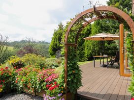 A garden with an archway and outdoor seating at Dan Castell Cottage in Llandeilo, Carmarthenshire