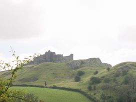A castle ruin on a hill surrounded by grass and trees at Dan Castell Cottage, Llandeilo, Carmarthenshire