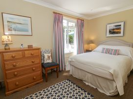 A bedroom with a bed, dresser, and chair at Dolwylan, Newport, Pembrokeshire
