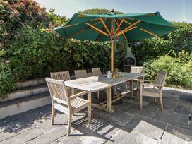 An outdoor dining area with a table and chairs under an umbrella at Dolwylan, Newport, Pembrokeshire