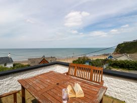 An outdoor space with a table and drink overlooking the ocean at Delyn Aur Tresaith, Ceredigion