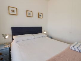 A bedroom with a bed and bedside lamp at Delyn Aur, Tresaith, Ceredigion