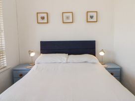 A bedroom with a bed and bedside lamps at Delyn Aur Tresaith, Ceredigion