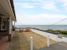 A patio area with table and chairs overlooking the sea at Delyn Aur, Tresaith, Ceredigion