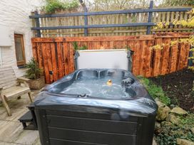 An outdoor hot tub with a rubber duck inside next to a wooden chair and wooden fence at Mill Barn Denant in Haverfordwest Pembrokeshire