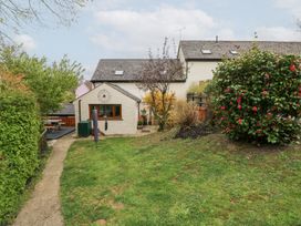 A garden with grass a path and a tree near a house with a patio at Mill Barn Denant in Haverfordwest Pembrokeshire