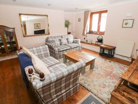 A living room with plaid sofas a wooden coffee table a large mirror and a patterned rug at Mill Barn Denant in Haverfordwest Pembrokeshire